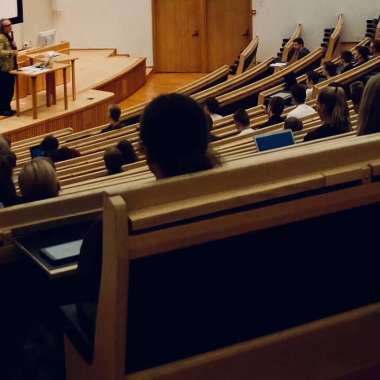 large mostly empty lecture hall with professor at front