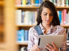 student with ipad in library