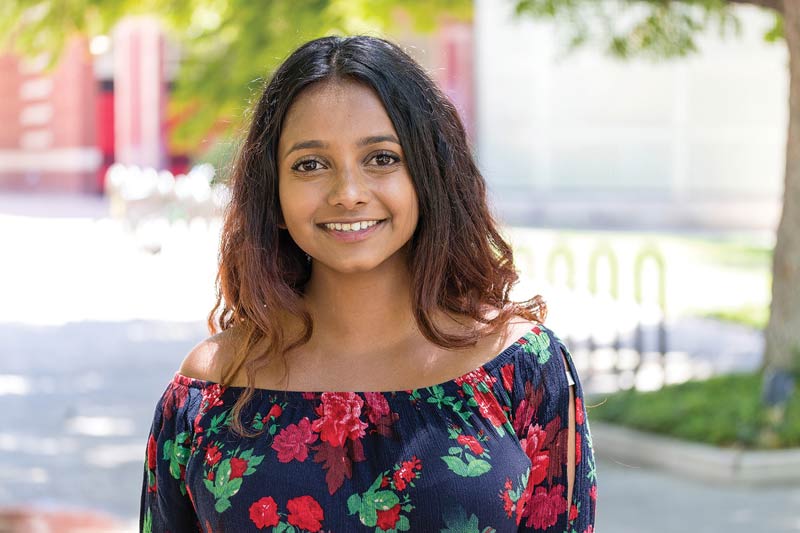 Psychology major, Viresha Perera in front of bike racks on the UCR campus