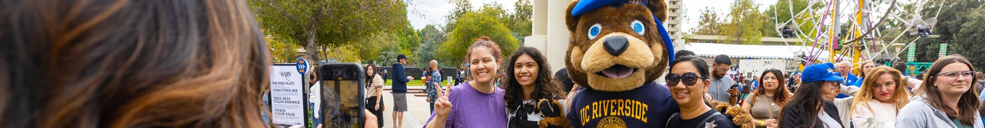 A family poses for a picture with UC Riverside's mascot, Scotty, a bear, during an event on the campus.