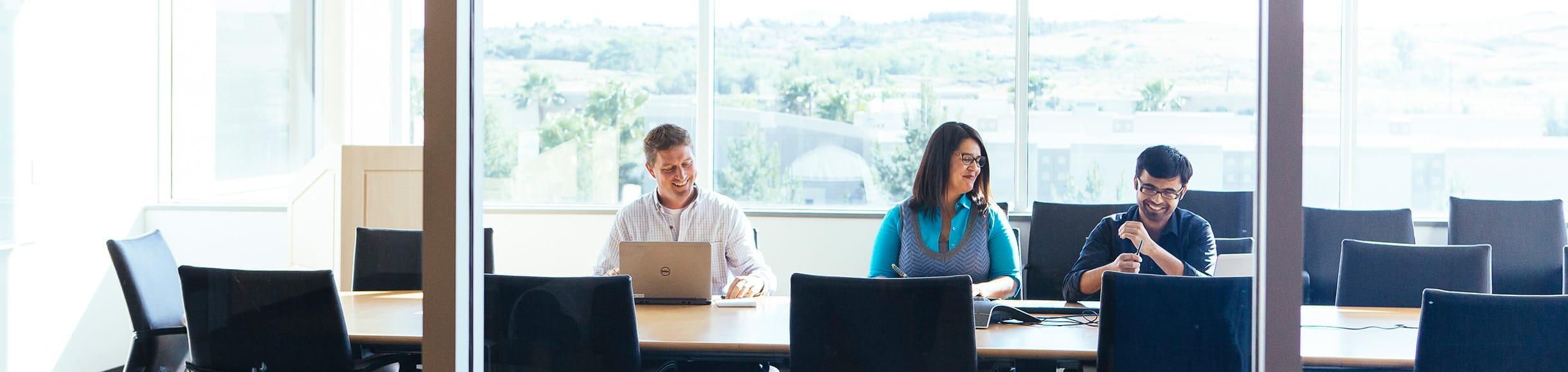 Group of people in a conference room on their computer and talking