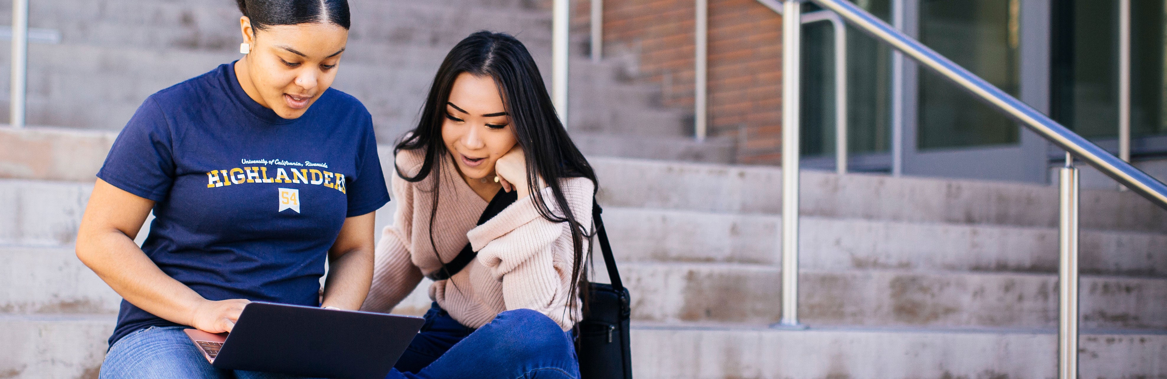 students sitting on steps looking at laptop (c) Elena Zhukova