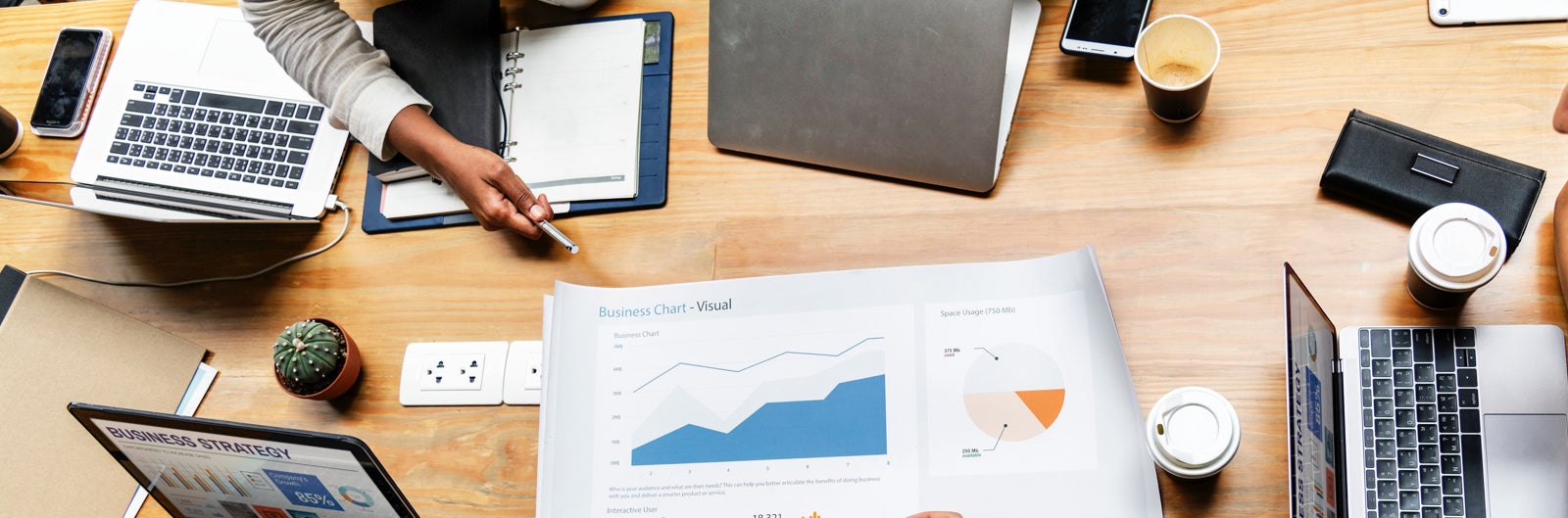 people at a table having a meeting, with laptops and notebooks