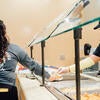 A student worker mixes food at Subway.