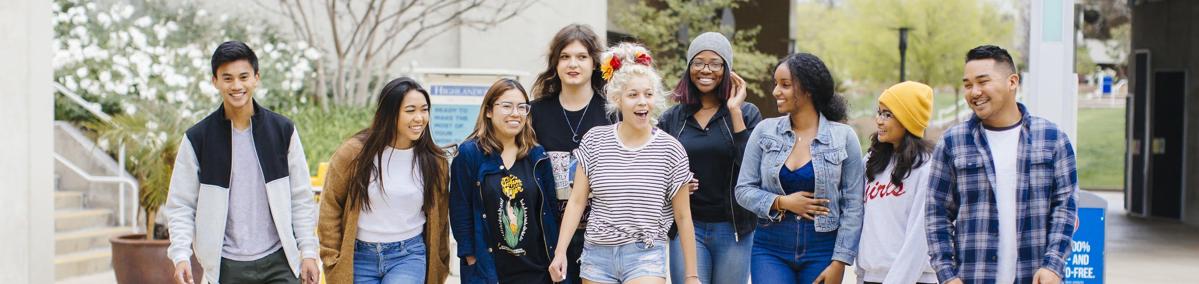 A group of students walking, talking, and smiling outside of Costo Hall on the UC Riverside campus.