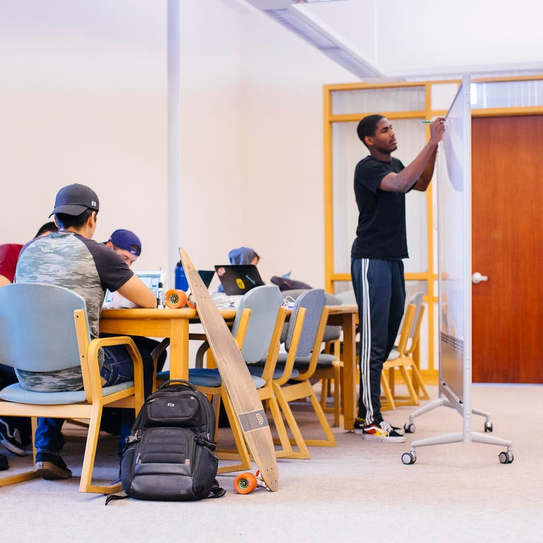 Students working at a table and using a white board