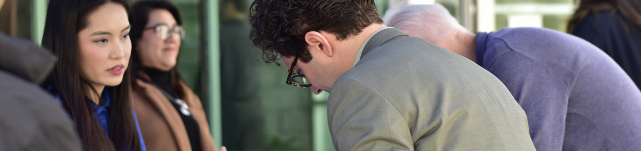 A woman in a blue jacket talking to a man at an outdoor event, with other people in the background.