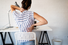 Woman sitting in chair holding her back