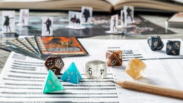 Dice and cards on top of a role-playing game character sheet. 