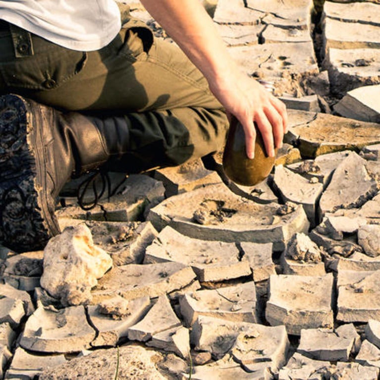 Image of person kneeling on cracked ground.