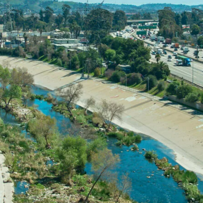 Aerial view of storm channel with water by freeway.