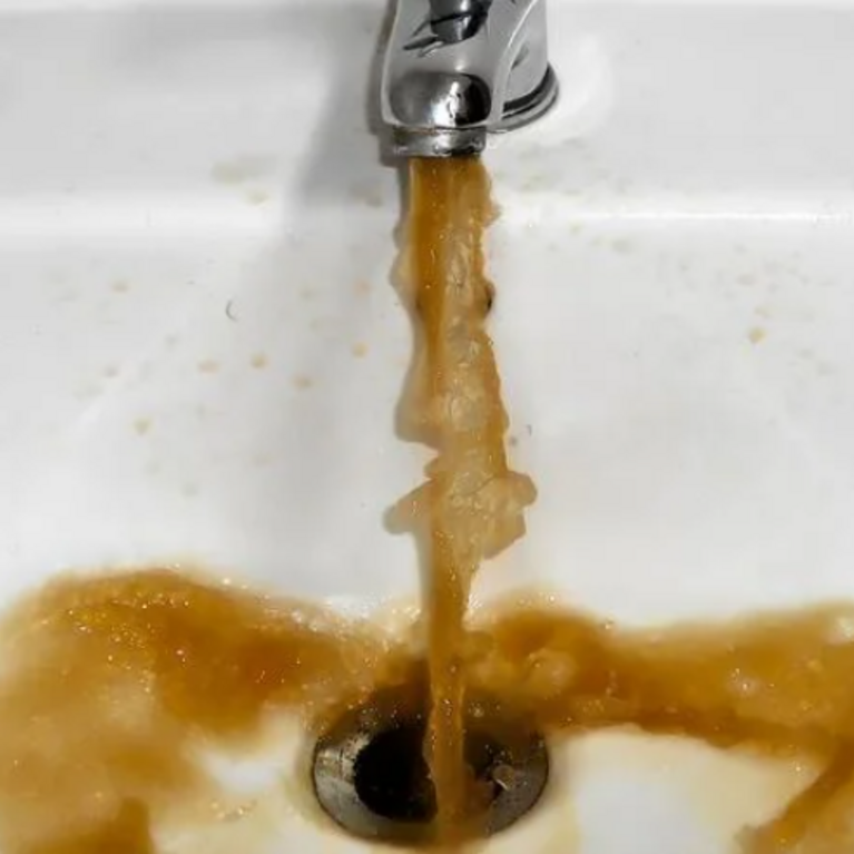 Dirty water pouring out of a sink faucet.