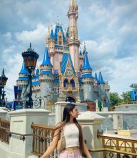 Smile Kaur standing in front of the magic castle at Disneyworld