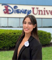 Smile Kaur standing in front of the Disney University sign wearing business attire