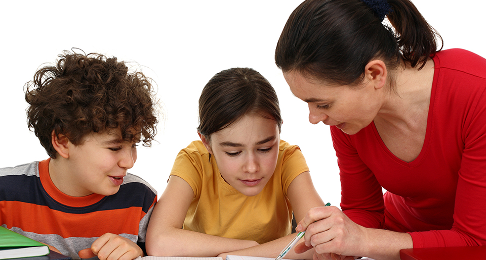 Two elementary children a boy and a girl looking down at something with a female teacher