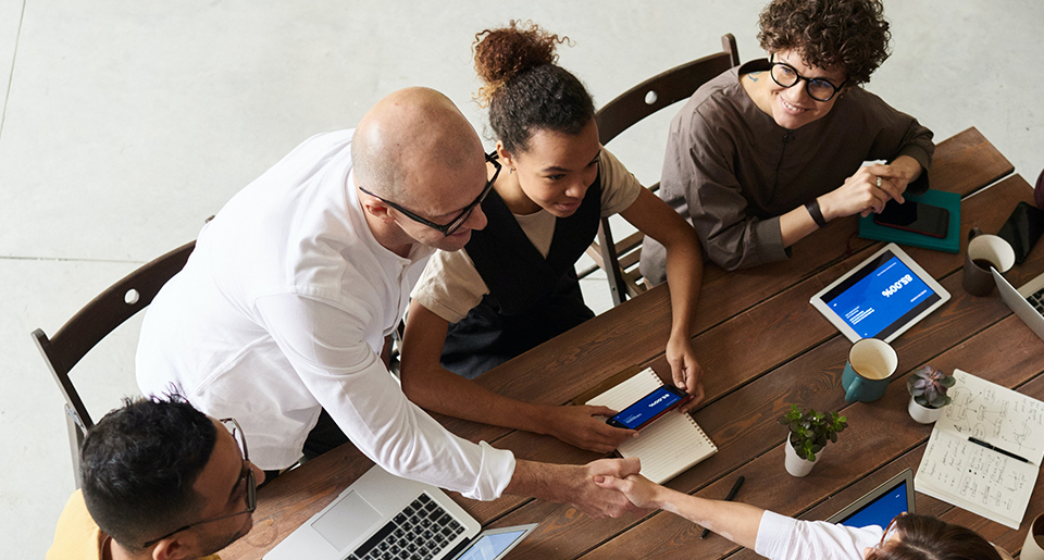 Business man and two women sitting at a table with laptops and tablets