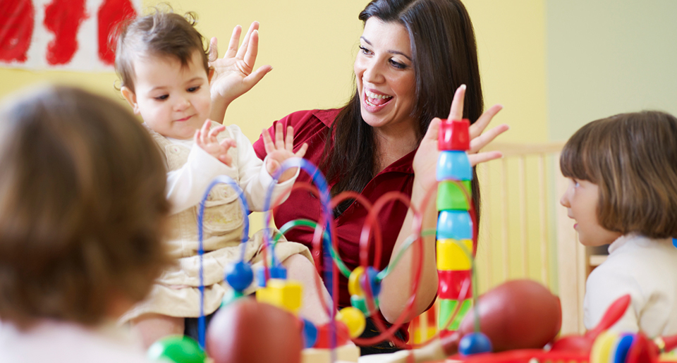 Young White woman playing a game of hands up with a baby and young children