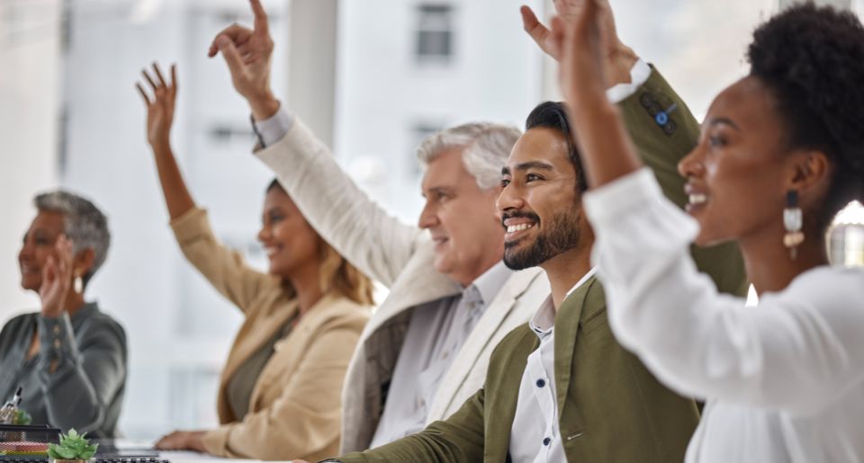 Seminar with group of diverse businesspeople raising their hands to engage in discussion
