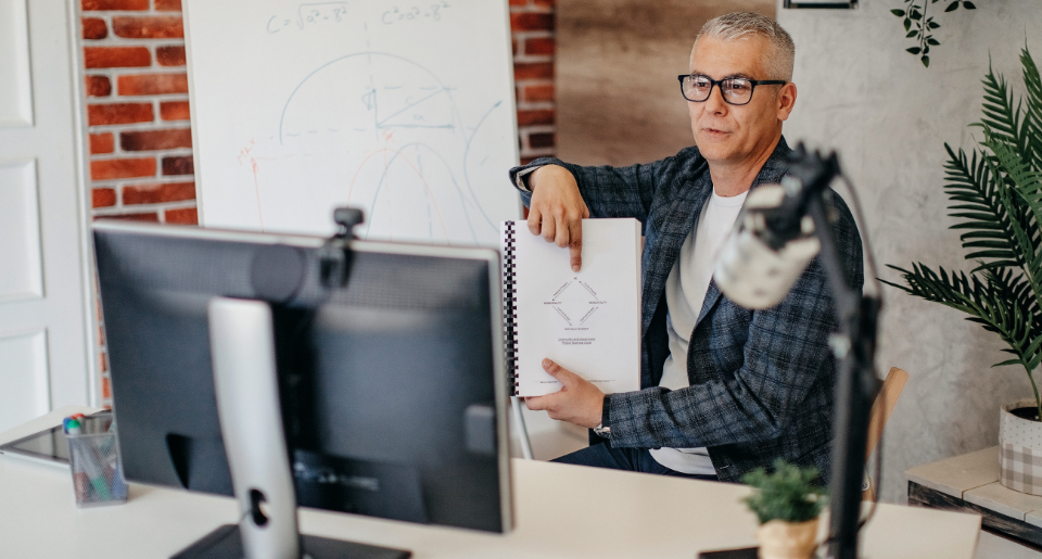 Male teacher pointing at a document while teaching online