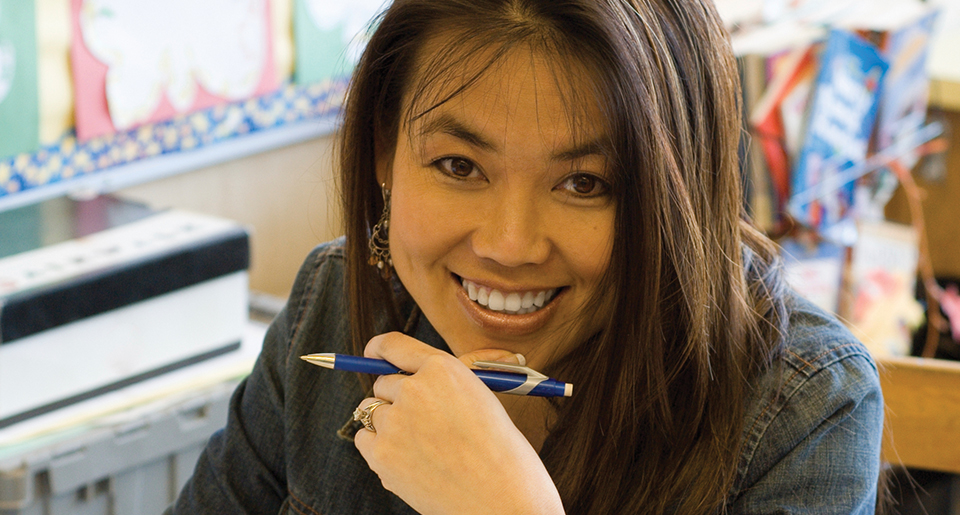 Up close of the face of a young smiling Hispanic female teacher in her classroom