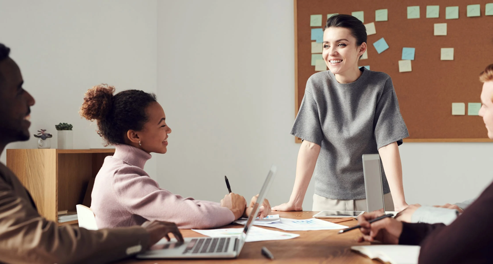 Young woman in classroom standing in front of bulletin board smiling