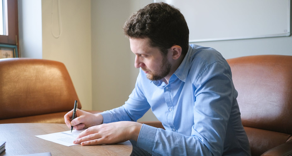 Business man writing on paper at desk