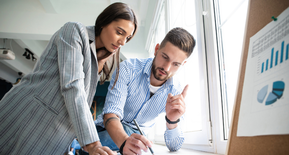 Female business woman looking at project plan with male businessman