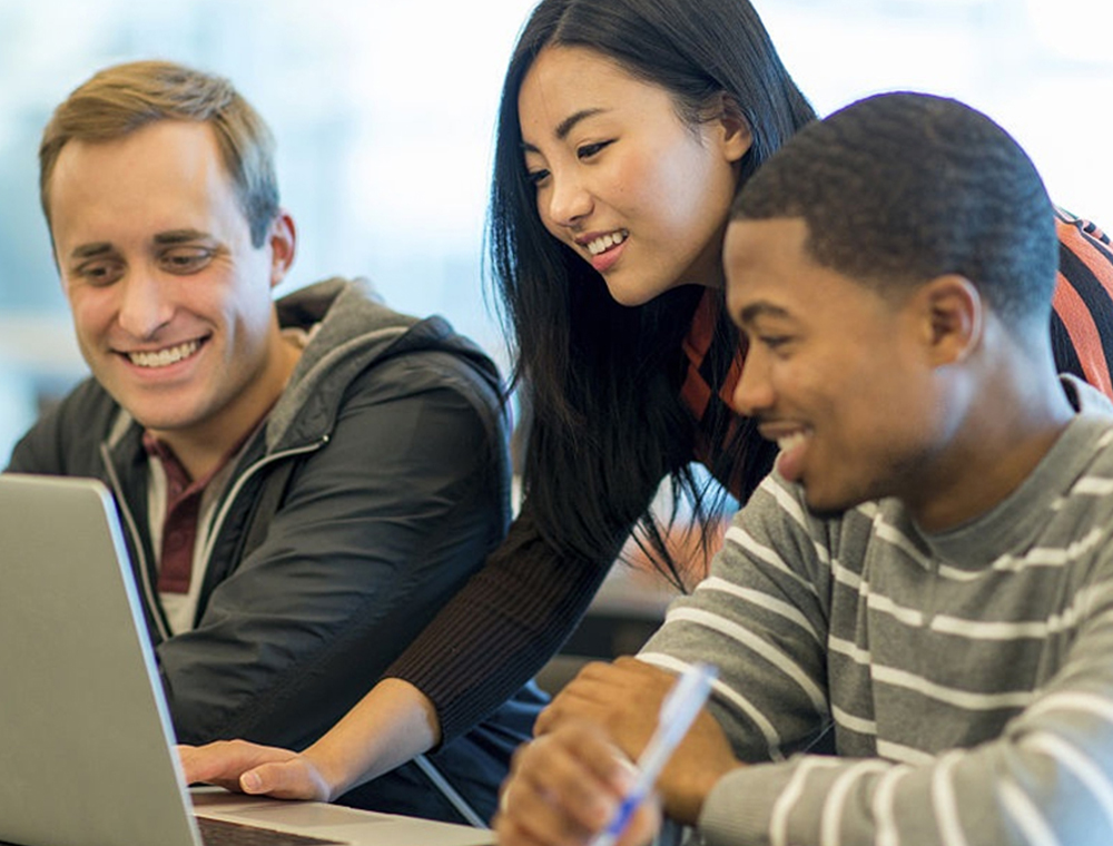 Three divers college students 2 men and on woman looking at a laptop together