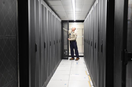 Electrician looking at rows of IT racks