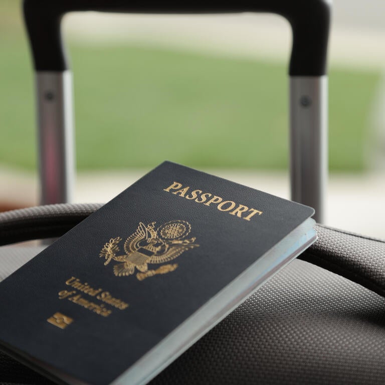 An American passport sits on top of a suitcase