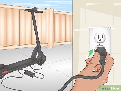 escooter charging cord being plugged into a outside outlet