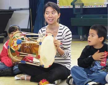 woman demonstrating a drum to a group of students