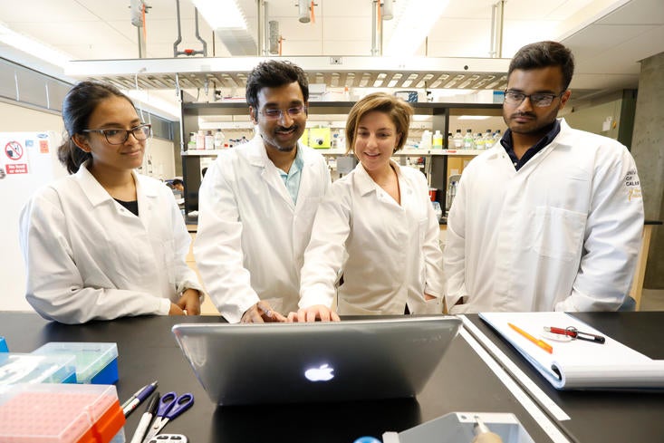 Students and Faculty gather around a computer in an engineering lab