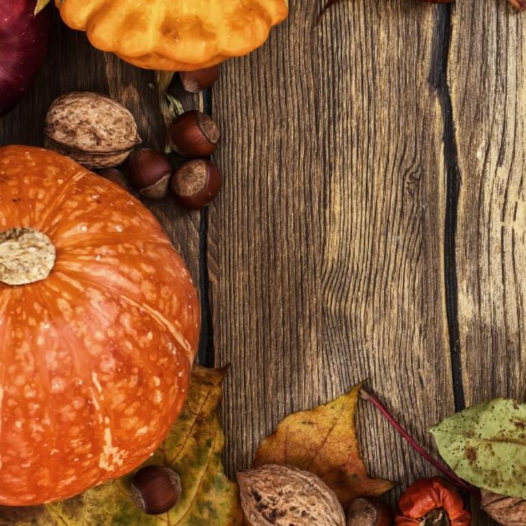 Aerial view of a wooden table with pumpkins and fall leaves