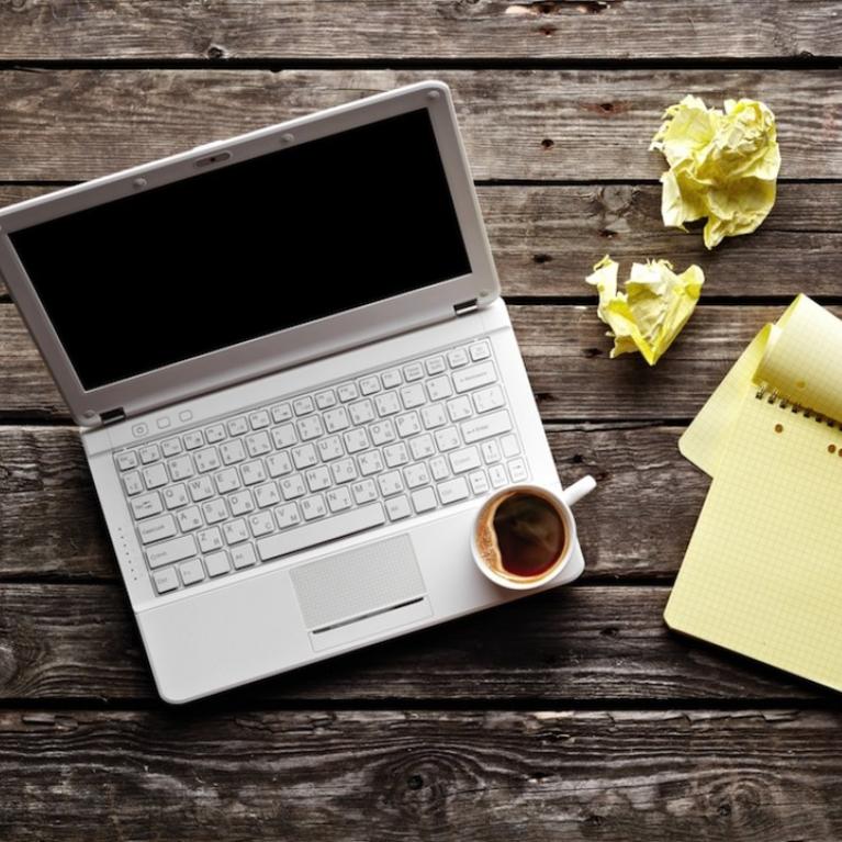 A desk with computer, paper, and coffee