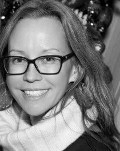 Professor Barbara Junisbai is pictured in black and white. She is looking smilingly at the camera with Christmas decorations behind her.
