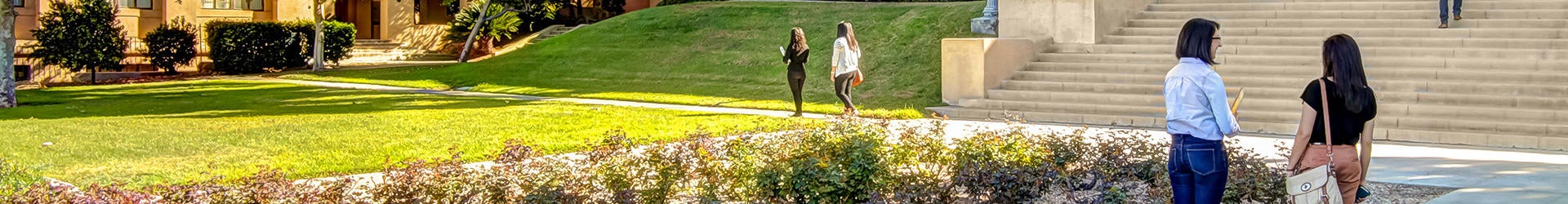 Panoramic view of UCR's parklike campus and students hanging out and walking to class.
