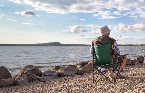 a man sitting in a chair and fishing in the ocean