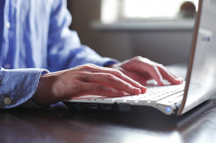 Close up of a mans hands as he types on his computer 