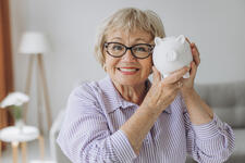 Savings Retirement and People Concept Smiling Senior Woman Holding Up A Piggy Bank