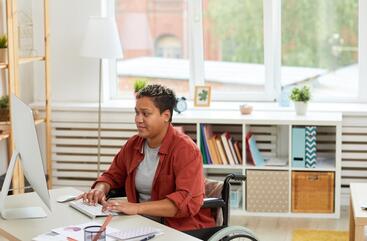 African American women with short hair typing on her keyboard while looking at her computer screen.
