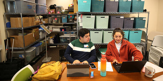 two students sitting on a desk and working