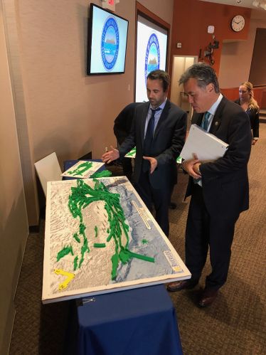 Christos Kyriakopoulos standing near display with Mark Takano.