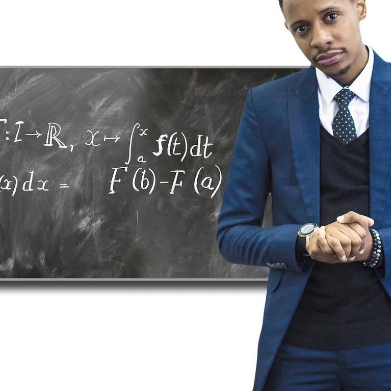 A teacher stands in front of a chalkboard