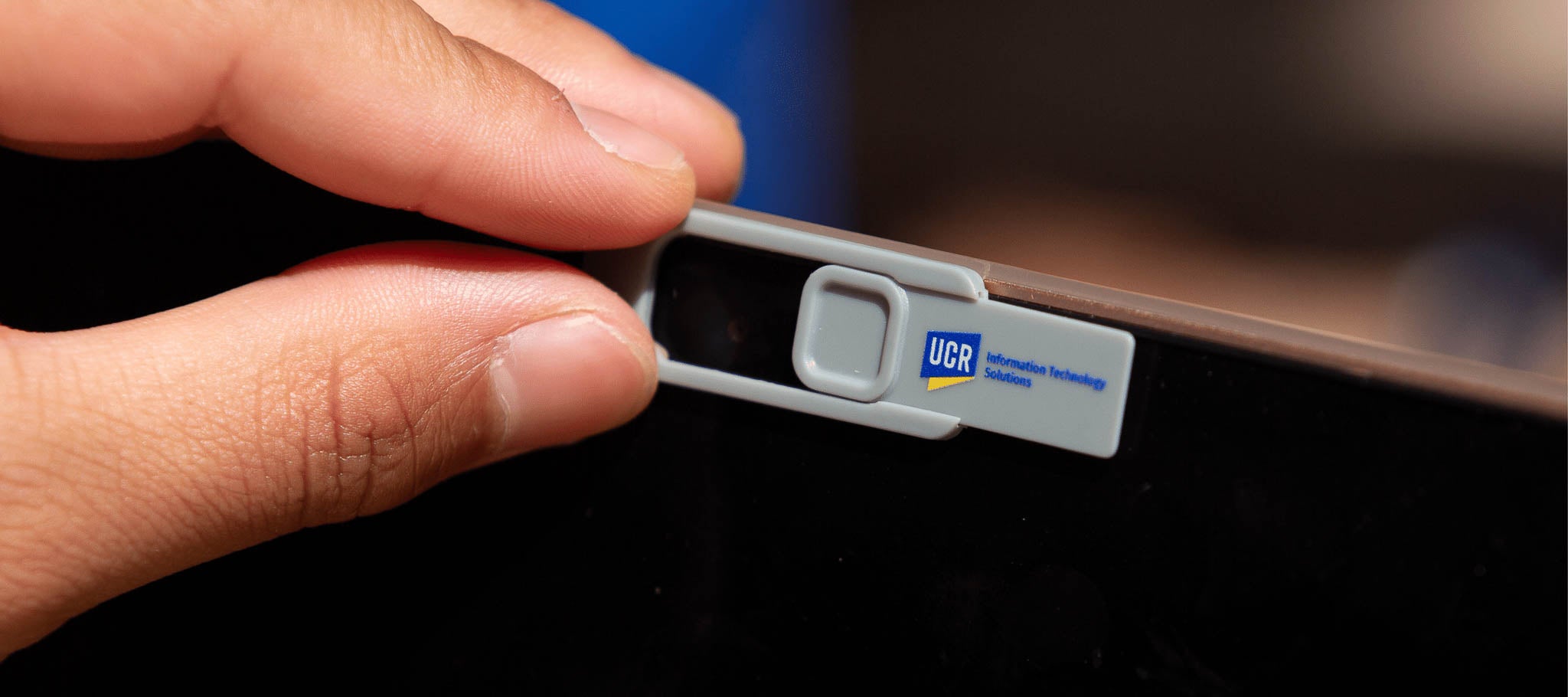 Hand places cover over laptop camera for protection