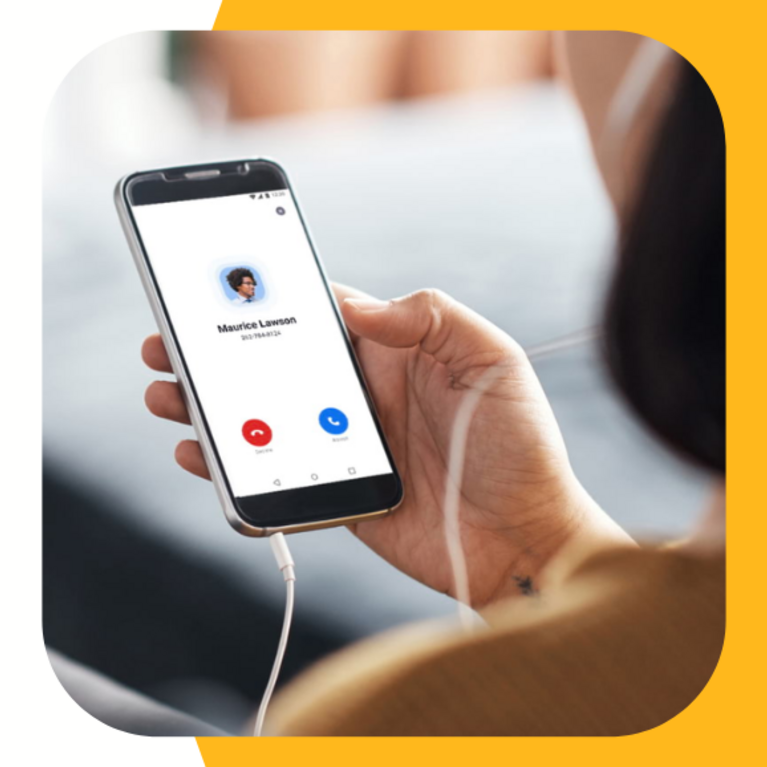 Zoom logo, person looking at smartphone screen, desk phone, and Zoom call on computer screen