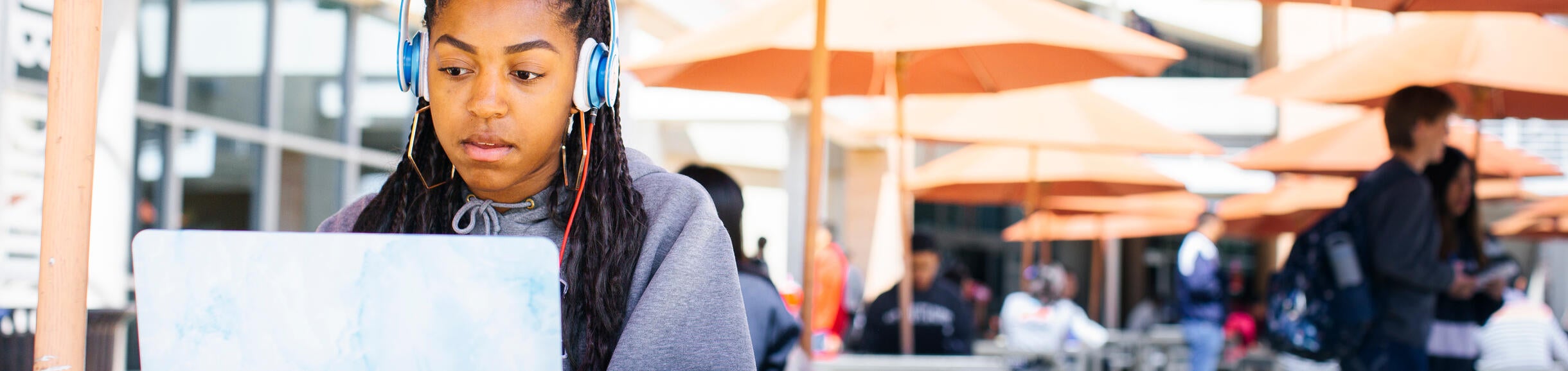 A student wearing headphones and on their laptop while sitting at the HUB