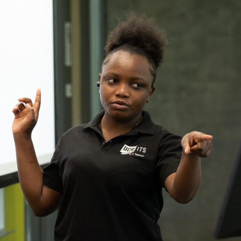 A worker in a black ITS Staff Shirt is giving a speech