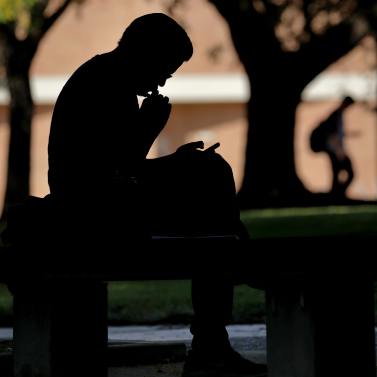 Silhouette of a student looking down at book
