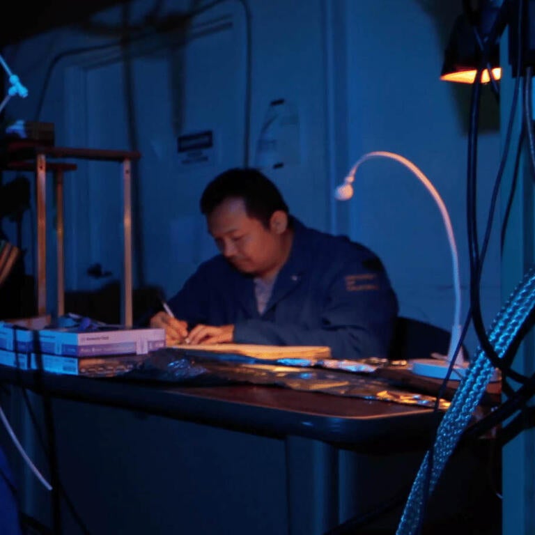 Two men a work in a room filled with tech equipment